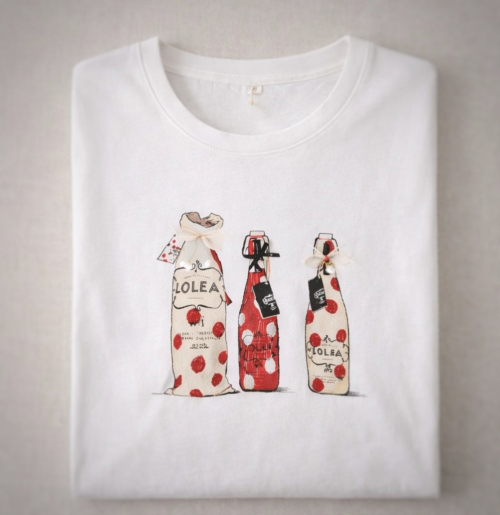 Detalle de la ilustración de botellas Lolea en camiseta blanca doblada