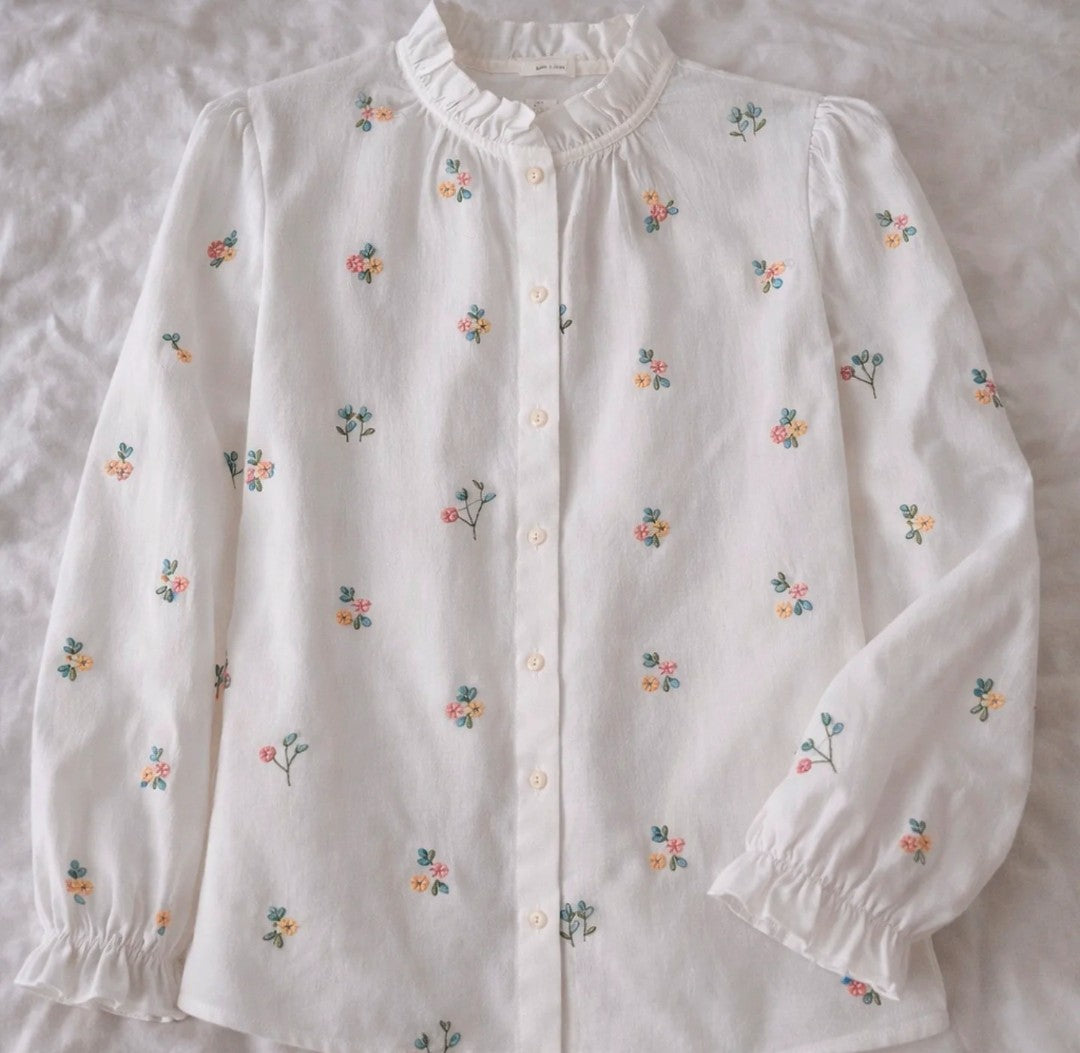 Blusa blanca con flores bordadas de colores vista completa sobre fondo neutro