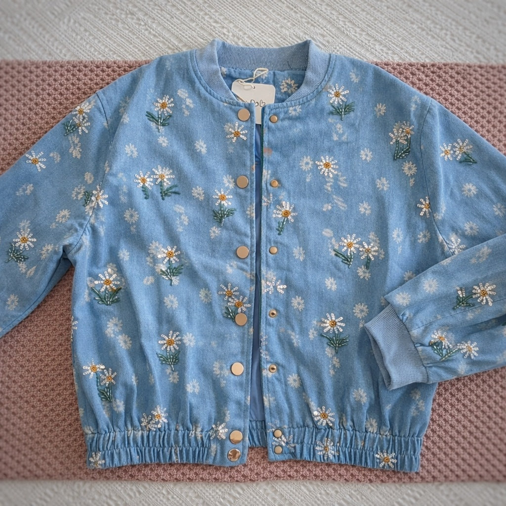 Bomber vaquera azul con margaritas bordadas vista completa sobre fondo neutro