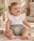 Bebé niña de 9 meses con conjunto Magnolia de algodón hecho a mano, blusa blanca con volantes y bloomer floral Conjunto Magnolia Petit Amour Blusa Magnolia Petit Amour