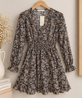 vestido paisley corto negro Vestido corto negro con estampado floral paisley, manga larga y cintura fruncida, colgado en una percha.