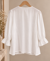 Blusa blanca con encaje Blusa blanca de manga tres cuartos vista por detrás, con tejido fluido y caída ligera